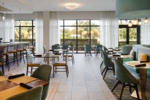 a dining room with tables and chairs and windows at EVEN Hotel Miami - Airport by IHG in Miami
