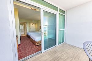 a room with a bed and a sliding glass door at Oceanfront Convenience on Lower Floor, Heated Pool in Myrtle Beach