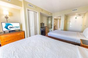 a hotel room with two beds and a flat screen tv at Oceanfront Convenience on Lower Floor, Heated Pool in Myrtle Beach