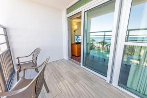 a balcony with a chair and a large window at Oceanfront Convenience on Lower Floor, Heated Pool in Myrtle Beach +55 photos