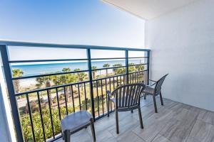 a balcony with a table and chairs and a view of the ocean at Oceanfront Convenience on Lower Floor, Heated Pool in Myrtle Beach