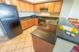 a kitchen with wooden cabinets and a black refrigerator at 2BR Pools, Direct Oceanfront Views, Handicap, Nice in Myrtle Beach