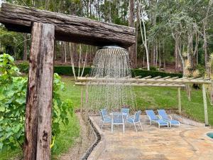 a fountain with chairs and a table in a garden at Fazenda Vale Dourado in Nova Friburgo