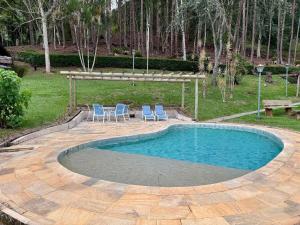 a swimming pool with two chairs and a table at Fazenda Vale Dourado in Nova Friburgo +115 photos