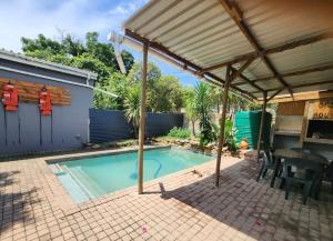 a patio with a swimming pool and an umbrella at CLR-Accommodation in George
