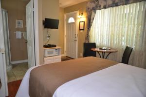 a bedroom with a bed and a table and a television at Motel Derfal in Repentigny