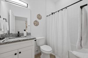 a white bathroom with a toilet and a sink at Cozy Coastal Cottage Minutes to Beach and Downtown in St. Augustine +39 photos