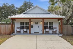 a white cottage with chairs and a porch at Cozy Coastal Cottage Minutes to Beach and Downtown in St. Augustine