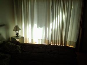 Un dormitorio con una cama y una ventana con cortinas. en Manilo House, en Mar del Plata