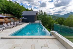 a swimming pool with chairs and a house at Cabanele CARMEL in Muntele Rece