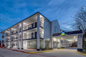 a large white building with a parking garage at SureStay Hotel by Best Western Spring North Houston in Spring