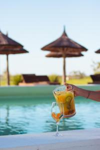 a person holding a drink next to a pool at Tramonto hotel & ristorante in Empedrado