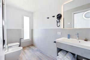 a white bathroom with a sink and a mirror at Luxea Guest House - B&B Treviso in Preganziol