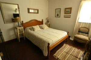 a bedroom with a bed and a mirror and a chair at Casa Amaranta in La Cumbre