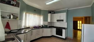 a kitchen with white cabinets and green walls at Abodes at 113 in Manzini