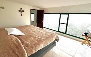 a bedroom with a bed and a cross on the wall at La Enamorada Cabañas & Resort in Zacatlán