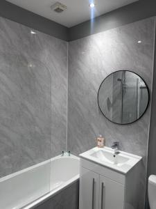 a bathroom with a sink and a tub and a mirror at House in Hemingfield, Ideal for Contractors and Long Stays in Wombwell +9 photos