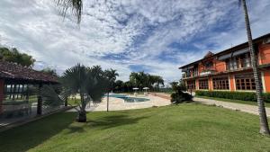 a house with a pool and a palm tree in the yard at Hotel Fazenda Lagoa Grande in Sete Lagoas