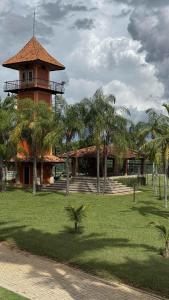 a building with a tower in a park with palm trees at Hotel Fazenda Lagoa Grande in Sete Lagoas