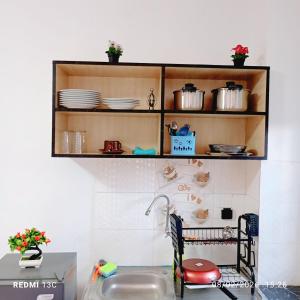 a kitchen with a sink and a shelf with dishes at Les studios américains d'Angré - 2 in Mandanou +2 photos