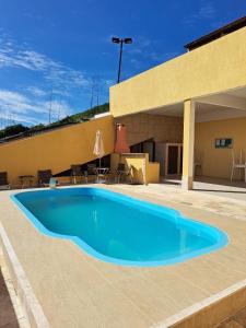 a large blue swimming pool in front of a building at Triplex com Piscina no Peró - Perto da Praia in Cabo Frio