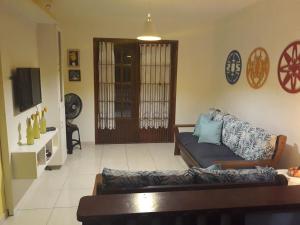 a living room with a couch and a tv at Triplex com Piscina no Peró - Perto da Praia in Cabo Frio