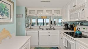 a kitchen with white cabinets and a sink at Gull Watch by AvantStay in Panama City Beach