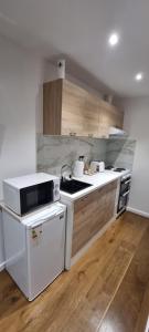 a kitchen with white appliances and wooden cabinets at Private Studio Suite, 24h Self Check-in in Luton +2 photos