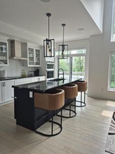 a kitchen with a black island with bar chairs at The Creek Home in Kemptville