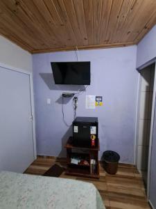 a bedroom with a bed and a tv on the wall at Suite Nomar centro in Brotas