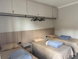 two beds in a room with white cabinets at Dallas hotel in Telêmaco Borba +4 photos