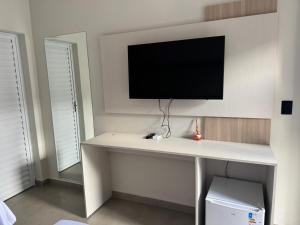 a white desk with a tv on a wall at Dallas hotel in Telêmaco Borba