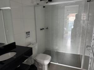 a white bathroom with a toilet and a shower at Dallas hotel in Telêmaco Borba
