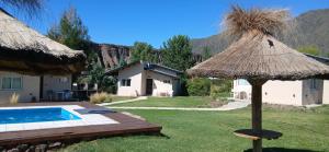 a resort with a swimming pool and a straw umbrella at Starry Lodge in Ciudad Lujan de Cuyo