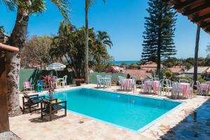 a swimming pool with chairs and a table and a table and chairs at Caminho das Pedras 206 in São Pedro da Aldeia