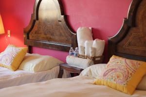 a bedroom with two beds and a mirror and pink walls at Casa Mestiza in Guadalajara