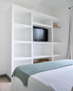 a bedroom with white shelves and a tv on the wall at Los Narcisos in San Antonio de Areco +16 photos