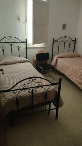 a bedroom with two beds and a chair and a window at Borgo marino litorale salus in Sciacca