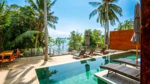 a pool at a resort with chairs and palm trees at Villa Amrita - Oceanfront Villa with Private Beach in Ko Phangan