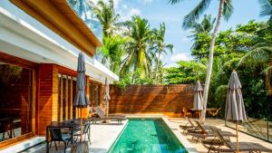a swimming pool with chairs and umbrellas next to a house at Villa Amrita - Oceanfront Villa with Private Beach in Ko Phangan