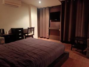 a bedroom with a bed and a table and a desk at Arizona Residence in Ban Ko En