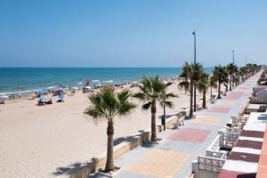 a beach with palm trees and people on the beach at Casa del Sol Miramar in Miramar