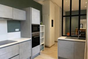 a kitchen with stainless steel appliances and a large window at Hôtel de Ville, T3, 2 chambres, 2 salles de bain in Saint-Étienne