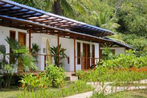 a house with a surfboard in a garden at Pacific Waves Hostel & Surf in El Valle