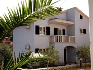 a white house with a palm tree in front of it at Villas Rab Palit in Rab