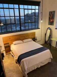 a bedroom with a bed and a large window at Lofty Hipster Penthouse in Johannesburg