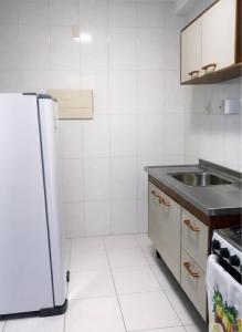a white kitchen with a sink and a refrigerator at Cantinho da Aruana, conforto e tranquilidade in Aracaju