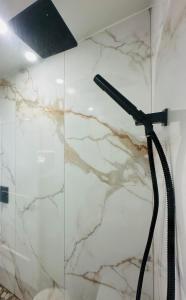 a shower with a black hose on a marble wall at Nubell Motel in Bell