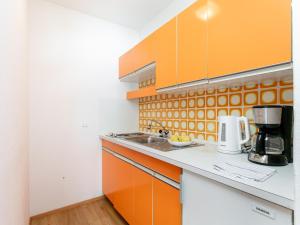 a kitchen with orange and white cabinets and a sink at Brixen Alpin Living Top 18 in Brixen im Thale