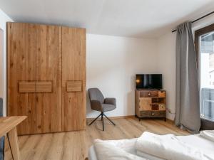 a bedroom with a large wooden cabinet and a chair at Brixen Alpin Living Top 19 in Brixen im Thale